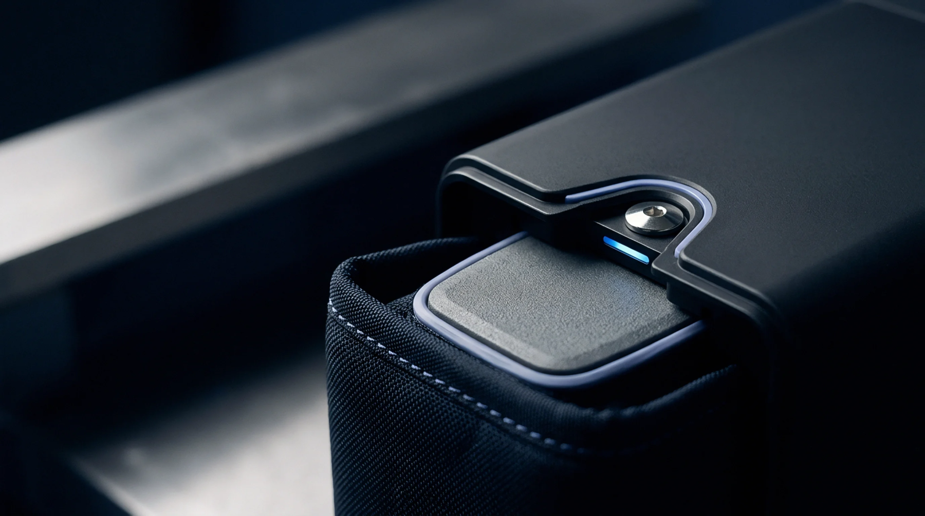 A dark grey prismatic battery cell slides partially into a textile wrapped housing secured by a metallic fastener with an active status indicator.
